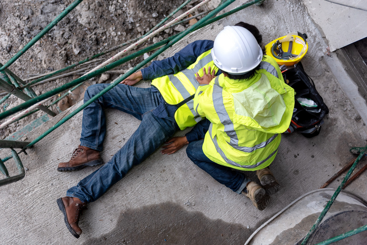 First aid support accident at work of construction worker at site. Builder accident falls scaffolding on floor, Safety team helps employee accident.