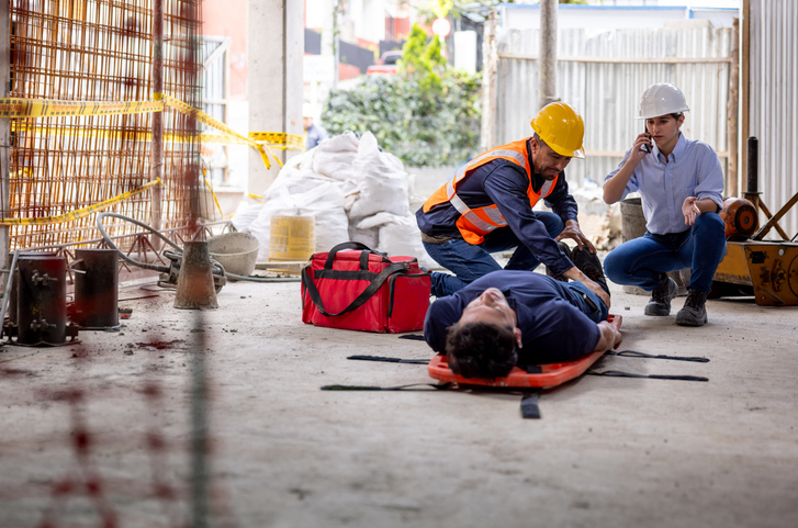 Safety team helping a builder having an accident at a construction site